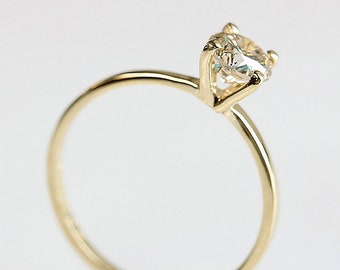 May include: A simple gold band ring with a single, clear, round gemstone set in a prong setting.