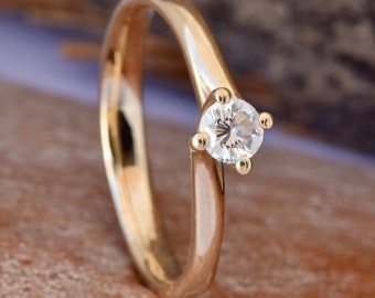 May include: A gold engagement ring with a single round diamond.