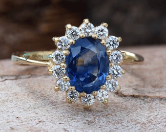 May include: A gold ring with a large oval blue sapphire surrounded by a halo of smaller diamonds.