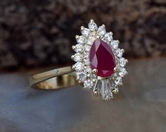 Op de afbeelding: Een gouden ring met een peervormige robijn, omringd door kleinere diamanten.
