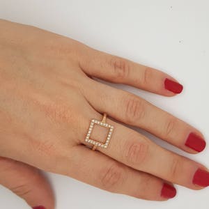 May include: A gold ring with a square-shaped setting of small clear stones.