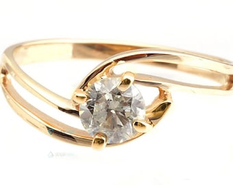May include: A gold ring with a single, clear, round gemstone set in a twisted band.