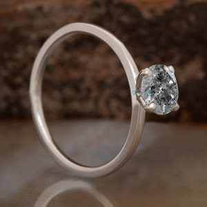 Puede incluir: Un anillo de plata con una sola piedra preciosa redonda y transparente.
