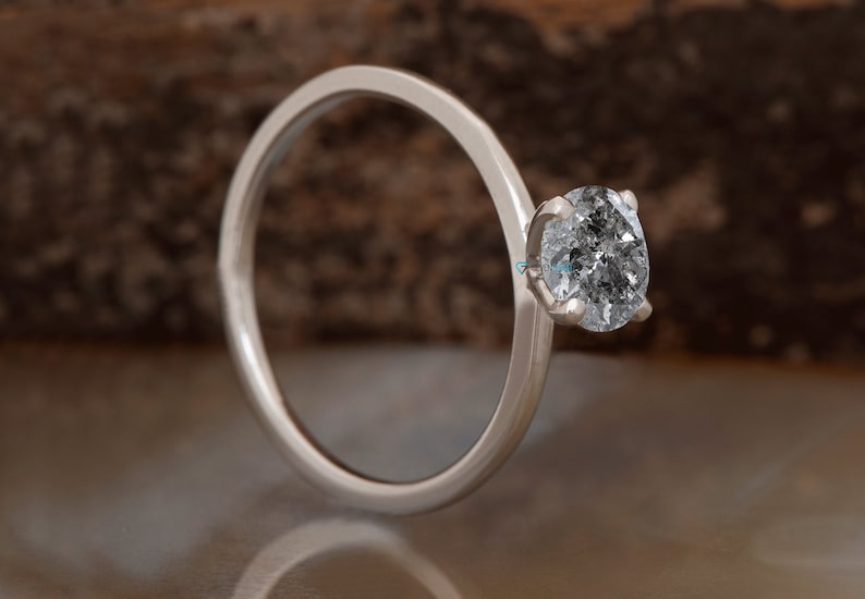 Puede incluir: Un anillo de plata con una sola piedra preciosa redonda y transparente.