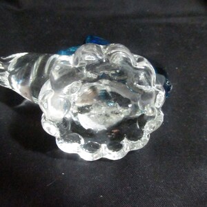 Puede incluir: Un tap&oacute;n de botella de vidrio transparente con una superficie texturizada y con burbujas. El tap&oacute;n tiene un acento de vidrio azul en la parte superior.