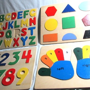 May include: Four wooden puzzle boards for children. The first board has the alphabet in colorful letters. The second board has the numbers 0-9 in colorful numbers. The third board has a variety of shapes in different colors. The fourth board has two hands with the numbers 1-9 on the fingers, labeled "left" and "right".