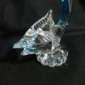 Puede incluir: Una escultura de vidrio de un pez vela azul con una base de vidrio transparente. El pez vela est&aacute; saltando fuera del agua con la cola levantada.