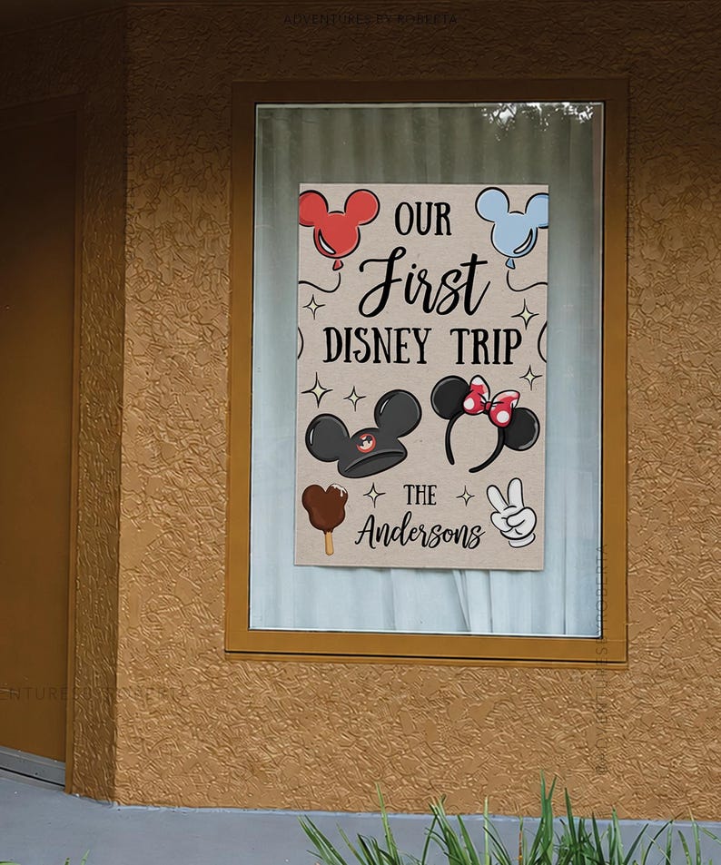 May include: A rectangular sign with the text "OUR First DISNEY TRIP" and "The Andersons" in a whimsical font. The sign features Mickey Mouse ears, a Mickey ice cream bar, and a peace sign.