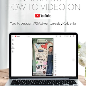 May include: A laptop screen shows a YouTube tutorial video. The video features the text "SAILING WITH THE MORAN FAM" and "REALLY CUTE DISNEY". The laptop is on a wooden table, with text above it saying "WATCH OUR HOW TO VIDEO ON YouTube.com/@AdventuresByRoberta".
