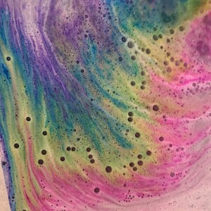 Rainbow cloud bath bomb color swirling in bath water.