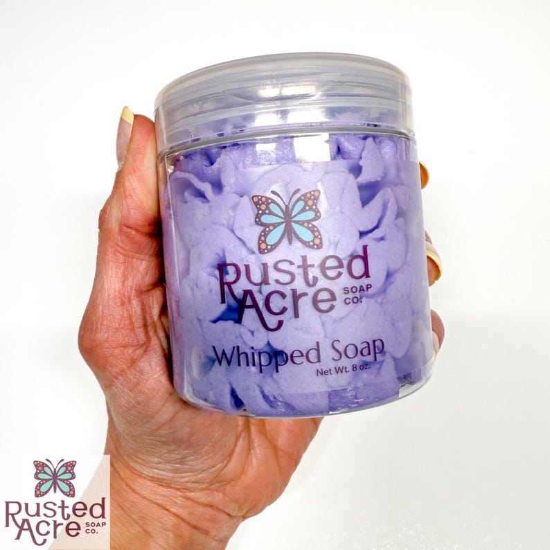 A jar of lavender vegan whipped soap handmade by Rusted Acre Soap Company in a hand.