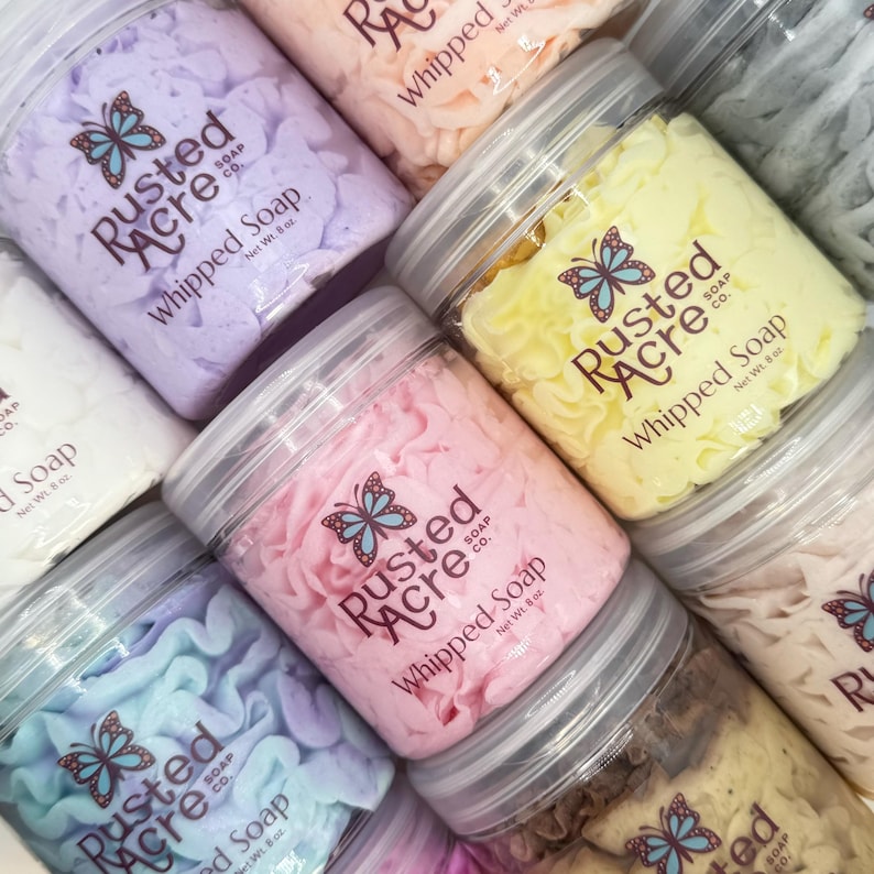 Multiple jars of whipped soap handmade by Rusted Acre Soap Co. Colors are pink, purple, yellow, teal, peach.