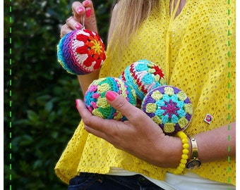 May include: Four colorful crocheted ornaments with a variety of floral patterns. The ornaments are made with different shades of pink, blue, green, yellow, and red yarn.