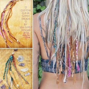 Puede incluir: Un conjunto de extensiones de pelo con clip de colores con plumas y conchas. Las extensiones están hechas de varios materiales, incluyendo hilo, cuero y plumas. El texto "CUSTOM CLIP-IN GYPSY DREADS BY SEA GYPSY DESIGNS" es visible en la imagen.