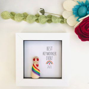 May include: A white frame containing a wooden figure holding a rainbow and a heart. The text inside the frame reads "Best Keyworker Ever! 2021".