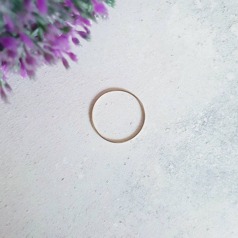 Puede incluir: Un anillo de oro simple sobre un fondo blanco.
