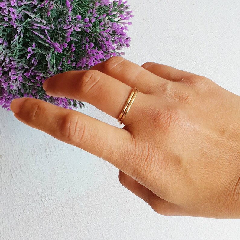 K&ouml;nnte beinhalten: Zwei d&uuml;nne goldene Ringe, die auf einem Finger &uuml;bereinander liegen.