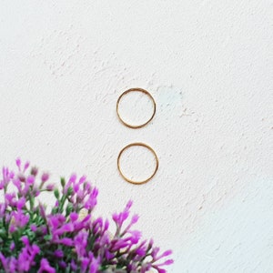 K&ouml;nnte beinhalten: Zwei goldene Ringe auf wei&szlig;em Hintergrund. Die Ringe sind schlicht und zart, mit einer glatten Oberfl&auml;che.