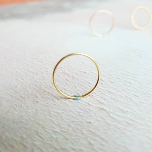 Puede incluir: Tres anillos de oro sobre una superficie blanca texturizada. El anillo del centro es un c&iacute;rculo simple, mientras que los dos anillos de la parte superior son texturizados.