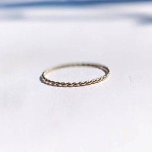 Op de afbeelding: Een dunne zilveren ring met een gevlochten ontwerp.