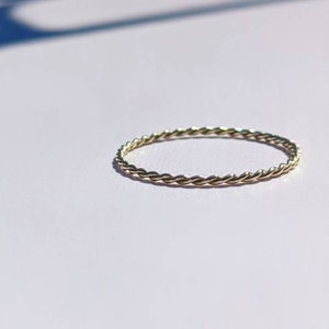 Op de afbeelding: Een dunne gouden ring met een gevlochten ontwerp.
