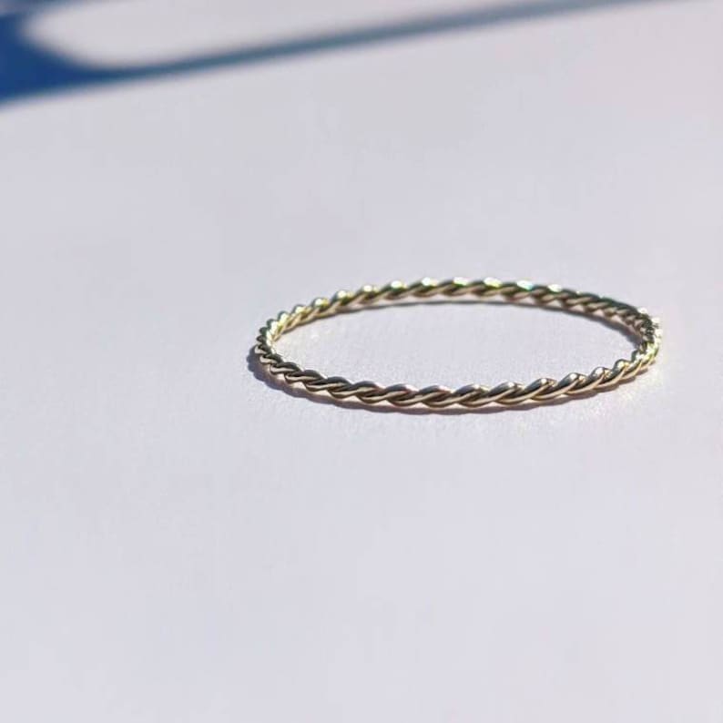 Op de afbeelding: Een dunne gouden ring met een gevlochten ontwerp.