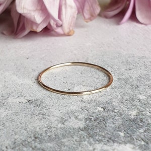 May include: A simple, thin gold band ring. The ring is smooth and has a polished finish.