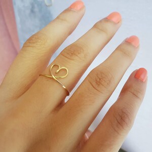 May include: A gold heart-shaped ring on a finger.