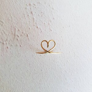 May include: A gold heart-shaped ring with a delicate wire design.