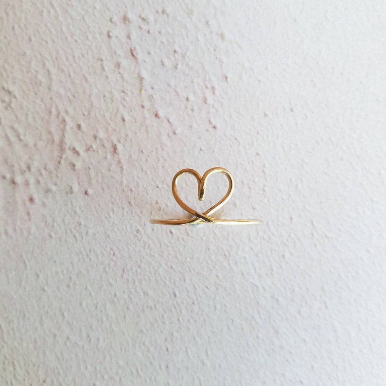 May include: A gold heart-shaped ring with a delicate wire design.