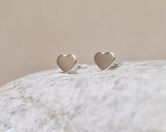 May include: A pair of silver heart-shaped stud earrings. The earrings are small and delicate, and they are perfect for everyday wear.