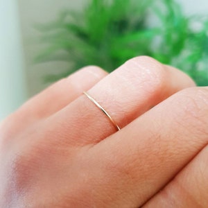 Puede incluir: Un anillo de banda de oro delgado usado en un dedo.