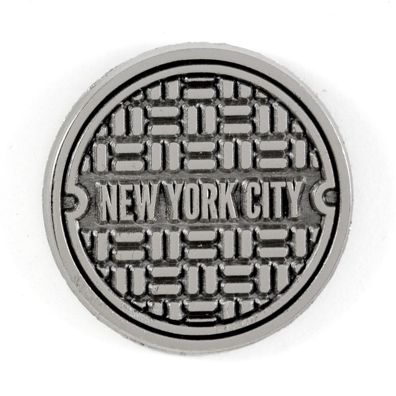 May include: A silver metal manhole cover with the words "NEW YORK CITY" embossed on it.