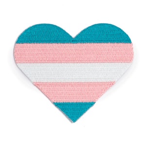 May include: A heart-shaped patch with the transgender pride flag colors: light blue, pink, white, pink, and light blue. The patch is made of fabric with a woven texture.