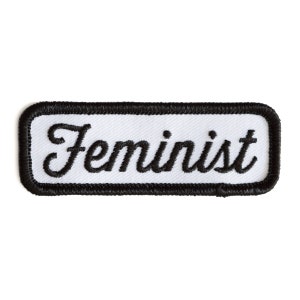 May include: White embroidered patch with black stitching and the word "Feminist" in a cursive font.