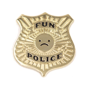 May include: Gold-colored metal police badge with the words "FUN POLICE" and a sad face emoji in the center.
