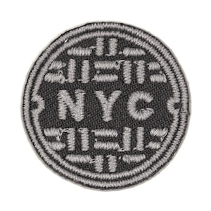 May include: A round, gray embroidered patch with the text "NYC" in white lettering inside a circle. The text "SUBWAY" is above the circle and the text "TILE" is below the circle.