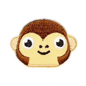 May include: A brown and yellow embroidered patch of a monkey's face with big eyes and a smile.