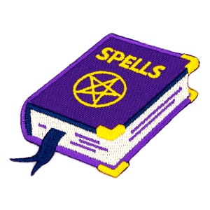 May include: A purple embroidered patch shaped like a book with the word "SPELLS" on the cover. A yellow pentagram is in the center of the cover. The book has a blue ribbon bookmark.