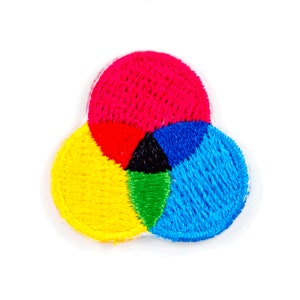 May include: Embroidered patch featuring a color wheel design. The patch showcases overlapping circles in red, yellow, and blue, with a black and green area in the center. The patch is on a white background.