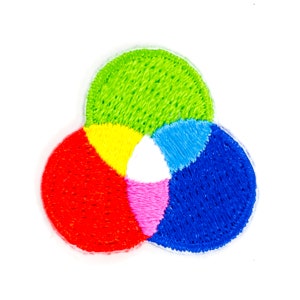 May include: Embroidered patch featuring a colorful design of overlapping circles. The patch showcases a vibrant palette of red, yellow, green, blue, pink, and white, with a white border. The design resembles a color wheel or a Venn diagram.