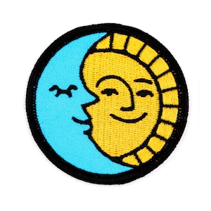May include: A black and yellow embroidered patch featuring a smiling sun and a crescent moon kissing. The sun has a yellow face with black eyes and a black mouth. The moon is blue with a black outline.