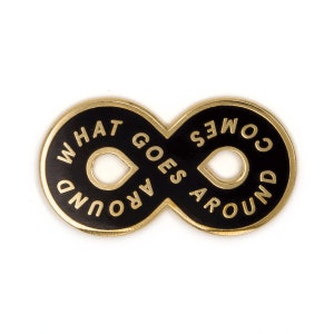 May include: Gold infinity symbol pin with black enamel and the text "What Goes Around Comes Around" in white.
