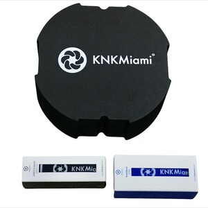May include: A black round container with the text "KNKMiami" and a white logo. Two rectangular boxes with the text "KNKMiami" and a white logo. The boxes are white with blue accents.