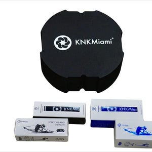 May include: Three white boxes with blue accents and the text "KNKMiami" on them. The boxes contain stretch bands and are labeled "Stretch Band Premium", "Stretch Band Ultra", and "Stretch Band Light". A black foam block with the text "KNKMiami" is also pictured.