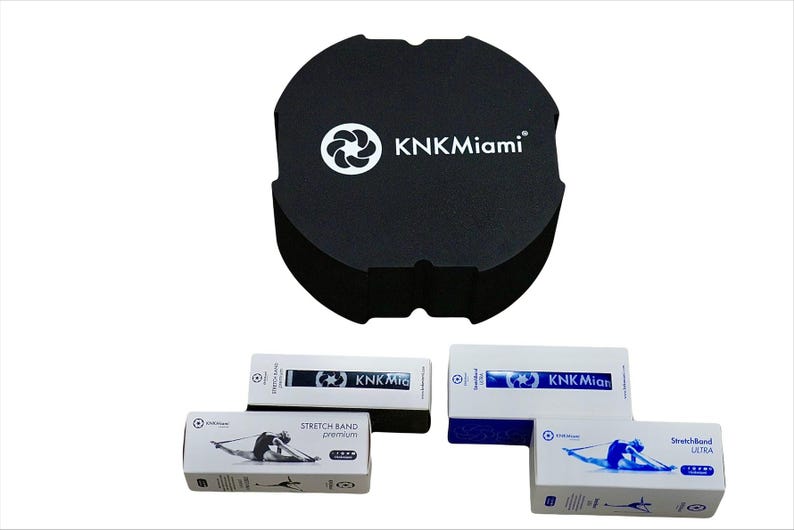 May include: Three white boxes with blue accents and the text "KNKMiami" on them. The boxes contain stretch bands and are labeled "Stretch Band Premium", "Stretch Band Ultra", and "Stretch Band Light". A black foam block with the text "KNKMiami" is also pictured.