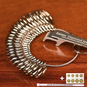 May include: A silver ring sizer with a bottle opener attached. The sizer has a range of sizes from 3 to 10. The sizer is on a wooden surface. The text on the bottle opener reads "Estate Diamond Jewelry" and "www.estatediamondjewelry.com".
