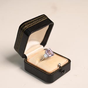 Verlovingsring met 2 karaat kunziet in het midden. Ring met smaragdgeslepen natuurlijke kunziet. Ring met twee trapeziumvormige diamanten. Handgemaakt in platina.