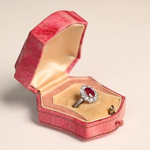 Puede incluir: Una taza de cerámica blanca con un asa negra y el texto "But First, Coffee" en un estilo manuscrito. La taza está sobre una superficie blanca. La taza mide aproximadamente 10 cm de alto.