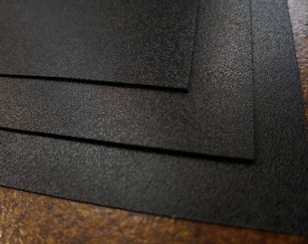May include: Three black textured sheets of paper stacked on top of each other.